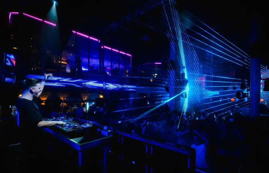 A DJ plays music at the Prater DOME nightclub, lit with blue laser lights
