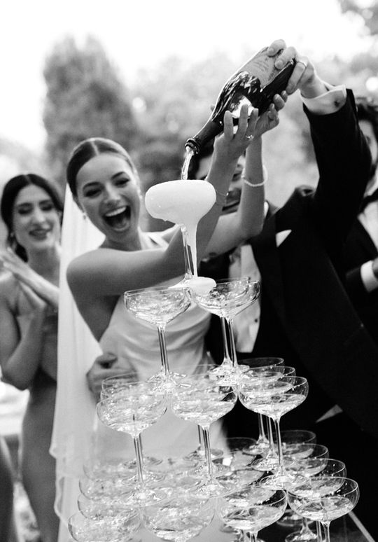 Bride pouring champagne into a tower at Graydon Manor Hall in Toronto, captured by fine art wedding photographers Hastings & King.