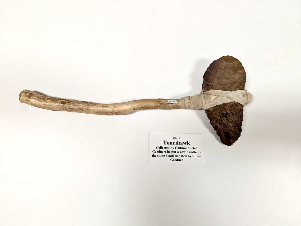 Close-up photo of a tomahawk from the McQuarrie Memorial Museum Indian Collection, once owned by Cannon ‘Pete’ Gardner and donated by Elinor Gardner. The tomahawk features a stone or bone-style head and a wooden handle.