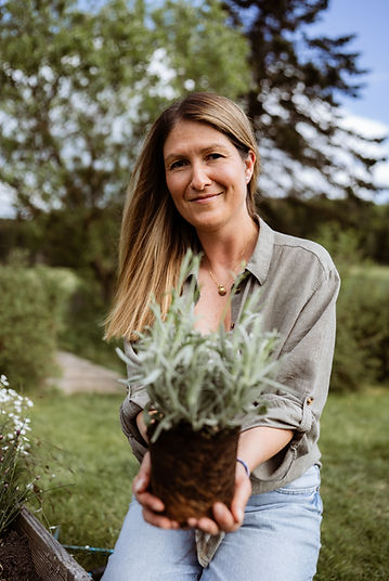 Frau sitzt im Garten und hält eine Lavendelpflanze – naturnahes Coaching-Umfeld mit Fokus auf Erdung und ganzheitlicher Begle