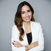 Smiling businesswoman in a white blazer posing confidently for a Chicago executive headshot against a modern gray studio background.
