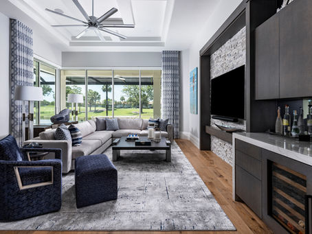 Modern custom home interior with open-concept living room, large windows, neutral seating, and built-in bar cabinetry.