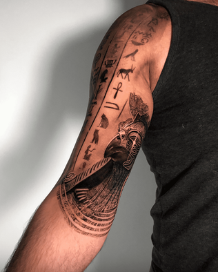 Tattoo of the statue of Horus on the upper arm in Black and White realism by APZ in Copenhagen, Denmark.In Copenhagen, APZ is a skilled tattoo artist trained by some of the best tattoo artists in the world. He specializes in classic realism tattoos using a modern black and white style, focusing on connected designs and full sleeve tattoos that enhance his clients’ style. His sculpture of Horus tattoo on upper arm speaks volumes with lifelike realistic details.