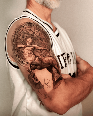 Tattoo of Sagittarius on upper arm in Black and White Realism by APZ in Copenhagen, Denmark.In Copenhagen, APZ is a skilled tattoo artist trained by some of the best tattoo artists in the world. He specializes in classic realism tattoos using a modern black and white style, focusing on connected designs and full sleeve tattoos that enhance his clients’ style. His Sagittarius tattoo on upper arm speaks volumes with lifelike realistic details.