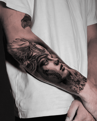 Tattoo of Valkyrie on forearm in Black and White Realism by APZ in New York, US.In New York, APZ is a skilled tattoo artist trained by some of the best tattoo artists in the world. He specializes in classic realism tattoos using a modern black and white style, focusing on connected designs and full sleeve tattoos that enhance his clients’ style. His sculpture Valkyrie tattoo on forearm speaks volumes with lifelike realistic details.