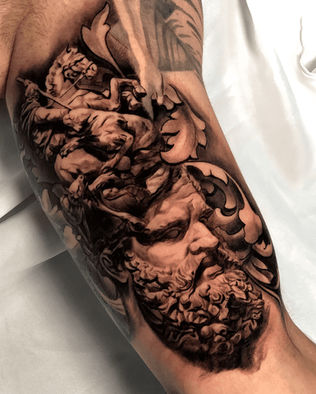 Tattoo of a Roman statue on the upper arm in Black and White realism by APZ in Copenhagen, Denmark.In Copenhagen, APZ is a skilled tattoo artist trained by some of the best tattoo artists in the world. He specializes in classic realism tattoos using a modern black and white style, focusing on connected designs and full sleeve tattoos that enhance his clients’ style. His Roman sculpture tattoo on upper arm speaks volumes with lifelike realistic details.