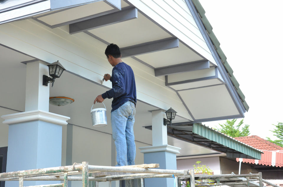 "Licensed painter working on the exterior of a luxury home in Redlands, CA with custom architectural details."