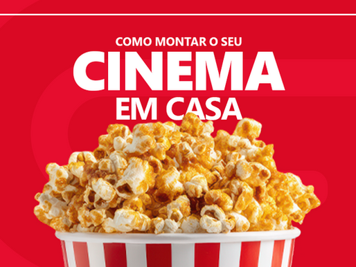 Banner de capa horizontal em fundo vermelho decorado com uma moldura branca retangular. Na parte superior, destaca-se a frase em letras garrafais brancas: "MONTE O SEU CINEMA EM CASA", posicionada logo acima de um balde listrado de vermelho e branco repleto de pipoca doce.