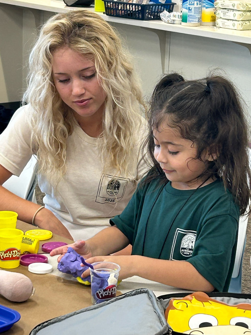 An ACN WE:PLAY intern engages with a camper during an art activity.