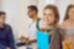 Smiling young woman with classmates in the background – classroom scene