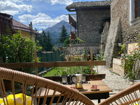 A view of Monte Chaberton from the back garden of the hideaway holiday apartments, from the Sauze d'oulx side. On the terrace there's an espresso Moka pot, a chair and table. The surrounding building is traditional Piemonte stone