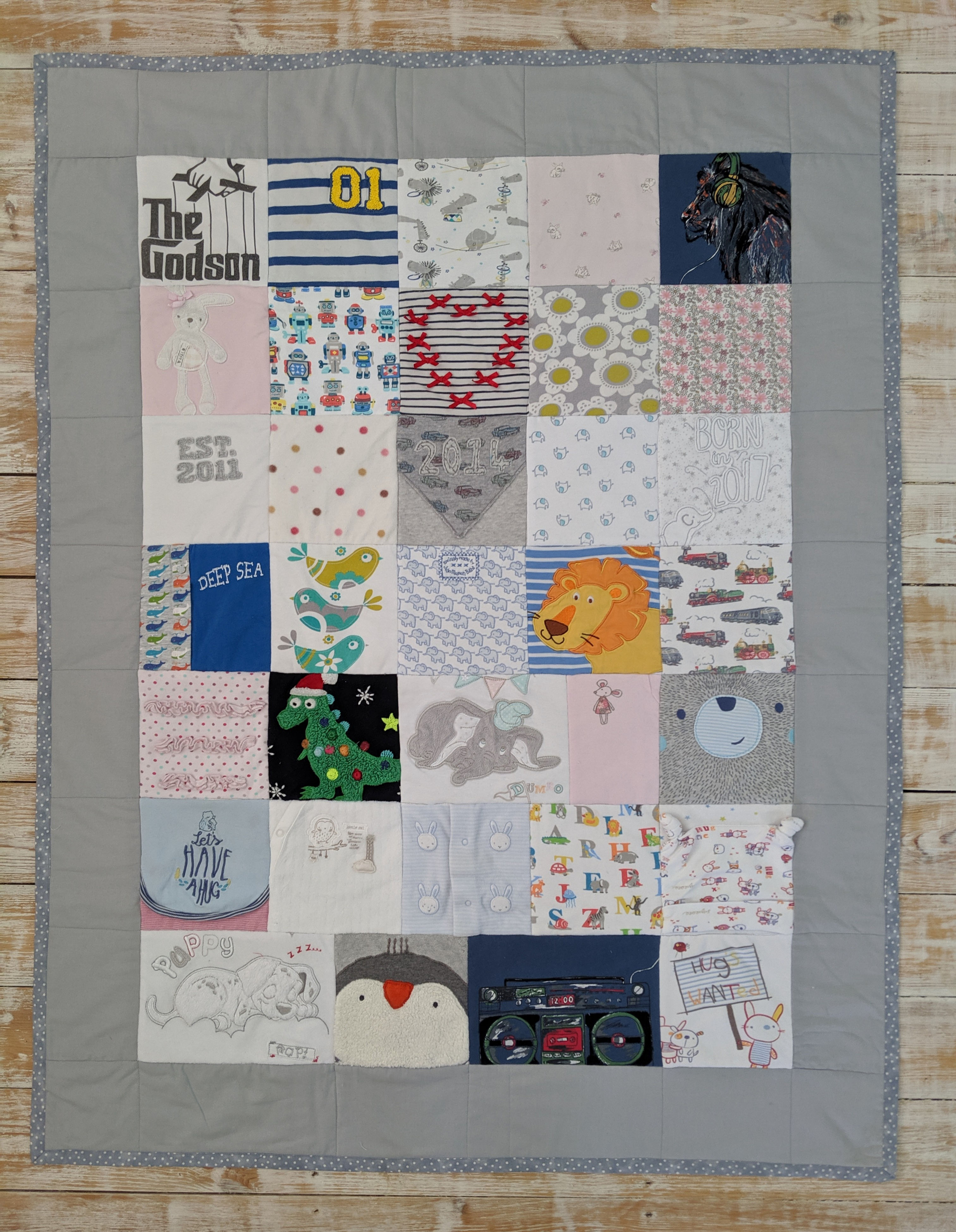 Medium keepsake quilt made with baby clothes. Framed with a plain grey border.