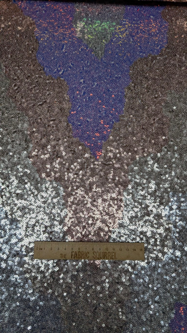 Thumbnail: Abstract pattern of silver and purple sequins with a wooden ruler.