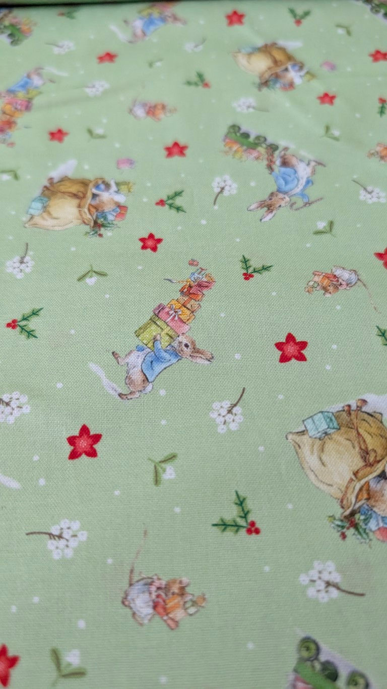 Green fabric with rabbits, gifts, stars, holly, and The Fabric Squirrel.
