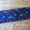 Thumbnail: Blue dinosaur fabric with various colorful shapes on a wooden background.