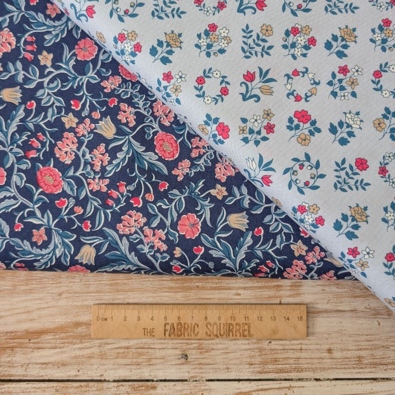 Thumbnail: Two floral fabrics with a ruler on wood surface, Sage Bauble Fabric - Snowfall from Figo Fabric.