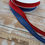 Thumbnail: Red and blue ribbon with The Fabric Squirrel ruler on wooden surface.