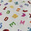 Thumbnail: Colorful printed alphabet letters and symbols on white fabric background.