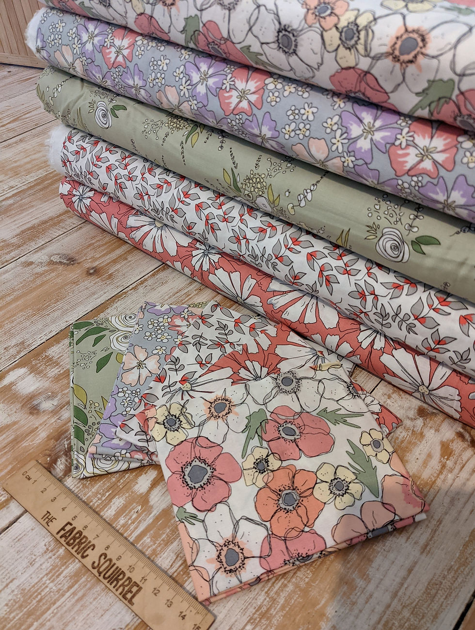 Thumbnail: Floral fabric stacks with multiple designs and colors on a wooden table.