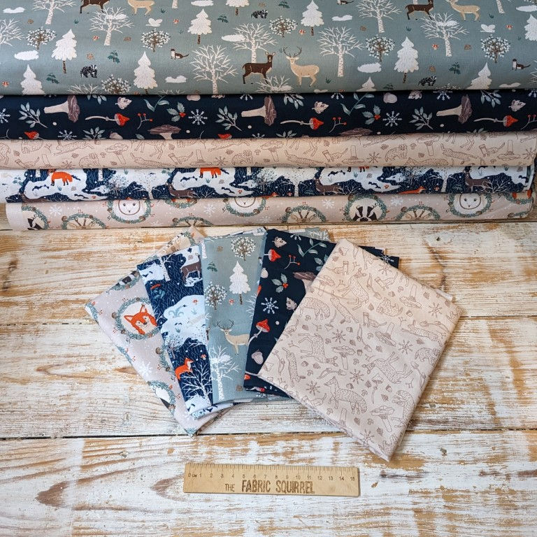 Thumbnail: Various winter-themed fabric rolls and folded swatches Wooden background fabric The Fabric Squirrel