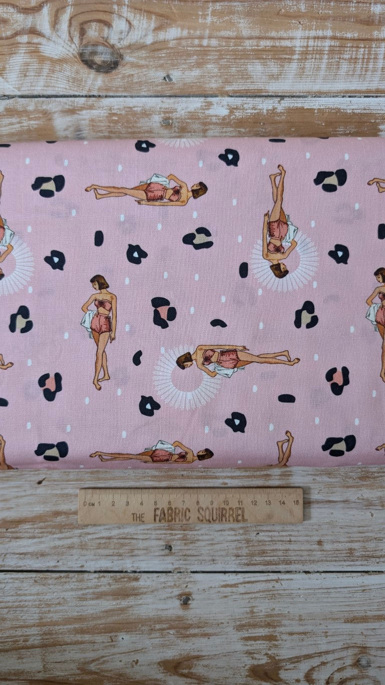 Thumbnail: Pink fabric with women and animal print, The Fabric Squirrel, on a ruler.