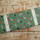 Thumbnail: Green fabric roll with rabbits and vegetables; Peter Rabbit. Wooden background.