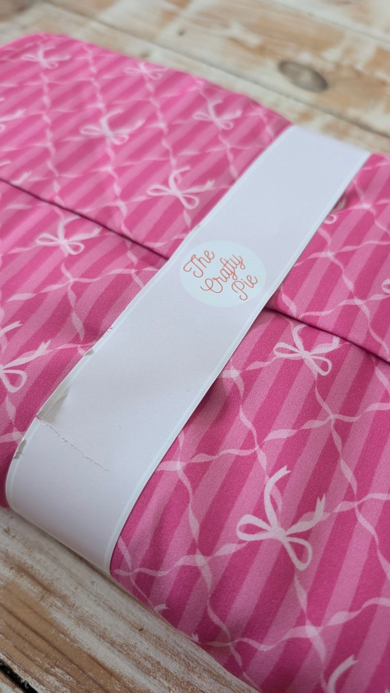 Thumbnail: Pink fabric with bows and stripe design, ribbon with text label.