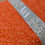 Thumbnail: Orange fabric with floral print and V&A text on a grey band.