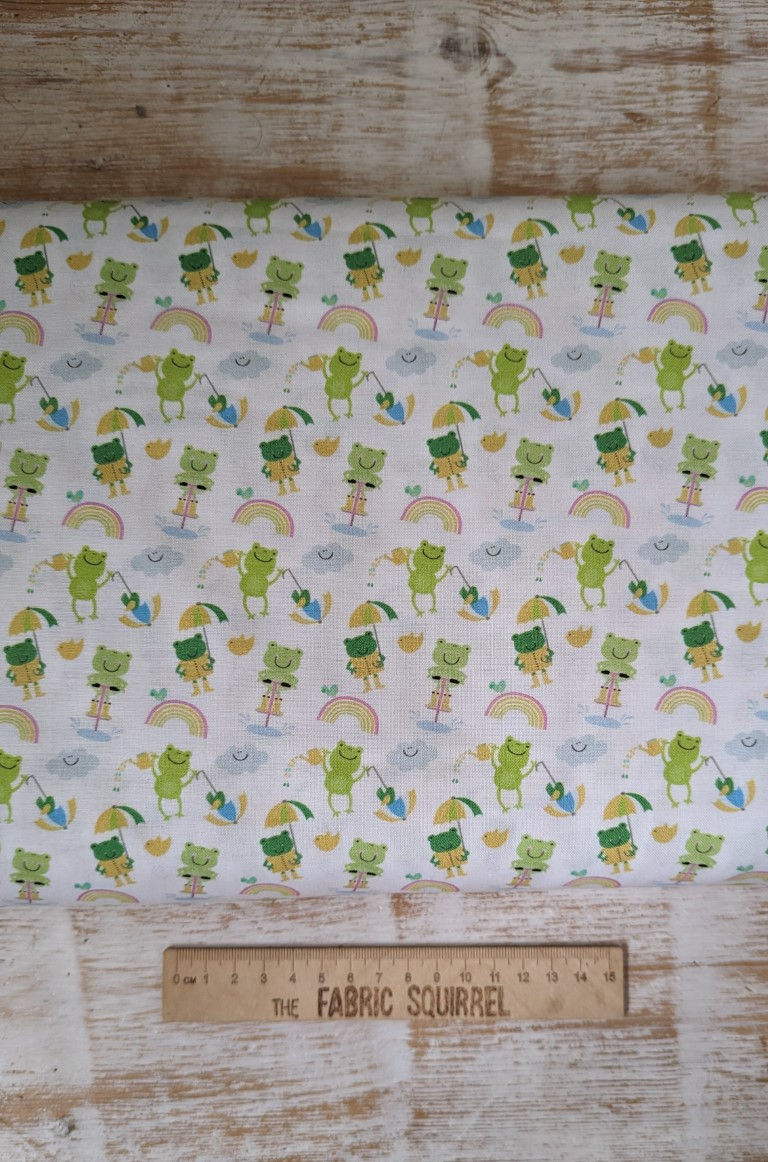 Thumbnail: Fabric with pattern of frogs, clouds and rainbows on a white background.