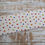 Thumbnail: Fabric with colorful fruit pattern on white background, displayed on wood.