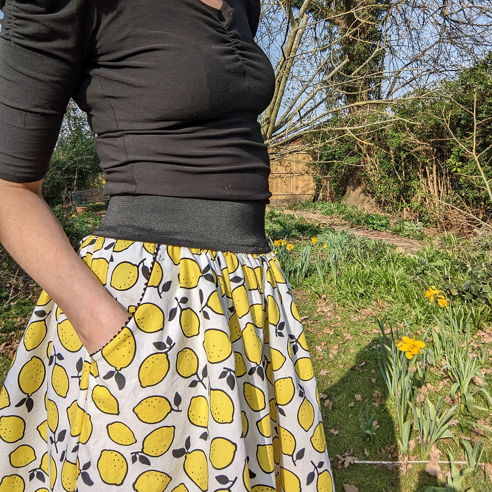 Woman wearing black top and lemon printed skirt with pocket, outdoor setting.