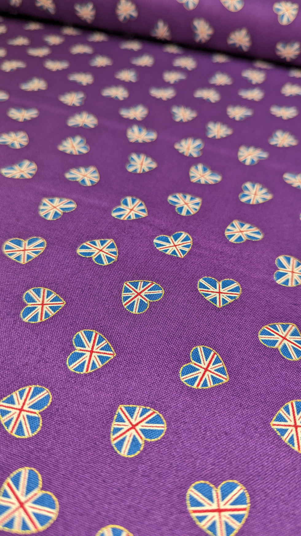 Thumbnail: Purple fabric scattered with heart-shaped Union Jack patterns; The Fabric Squirrel.