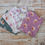 Thumbnail: Various floral fabric cuts on a wooden surface, Red Floral Fabric - Rainbow Garden Organic Cotton The Fabric Squirrel