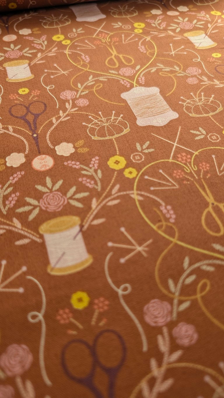 Thumbnail: Fabric with sewing supplies and flowers pattern on brown background.
