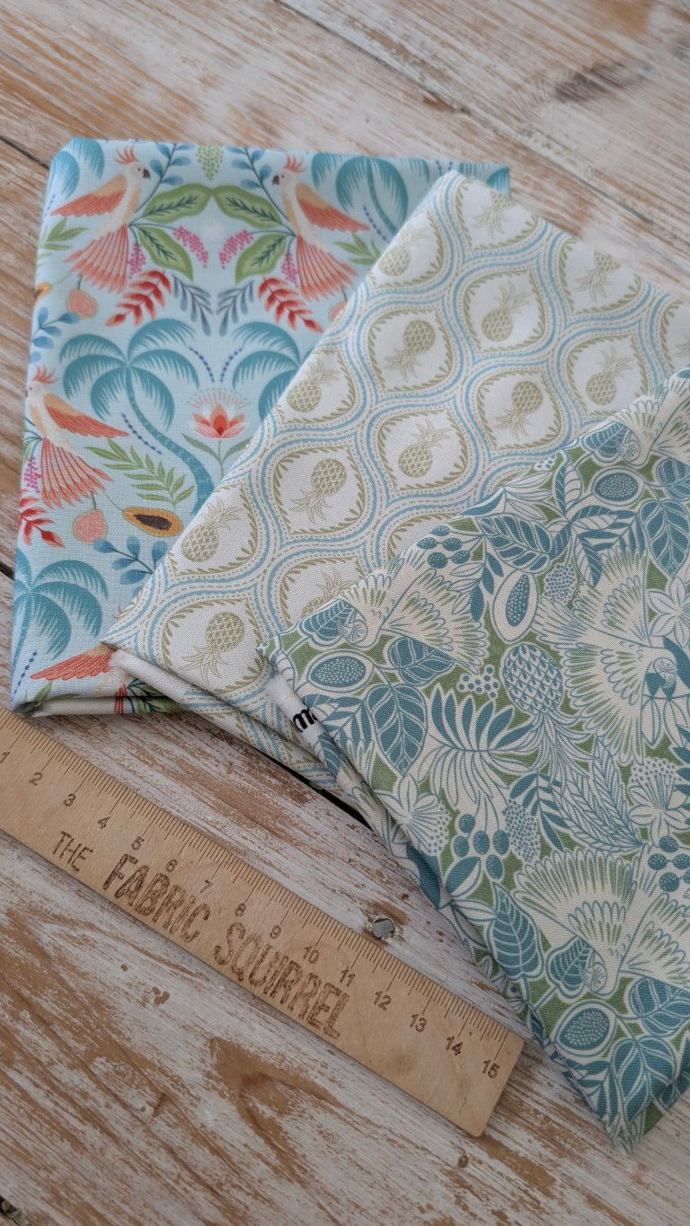 Thumbnail: Fabric swatches with tropical patterns and The Fabric Squirrel ruler, close-up shot.