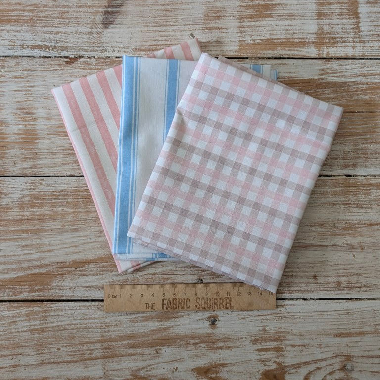Thumbnail: Three fabrics on wooden table with pink, blue, and white patterns.