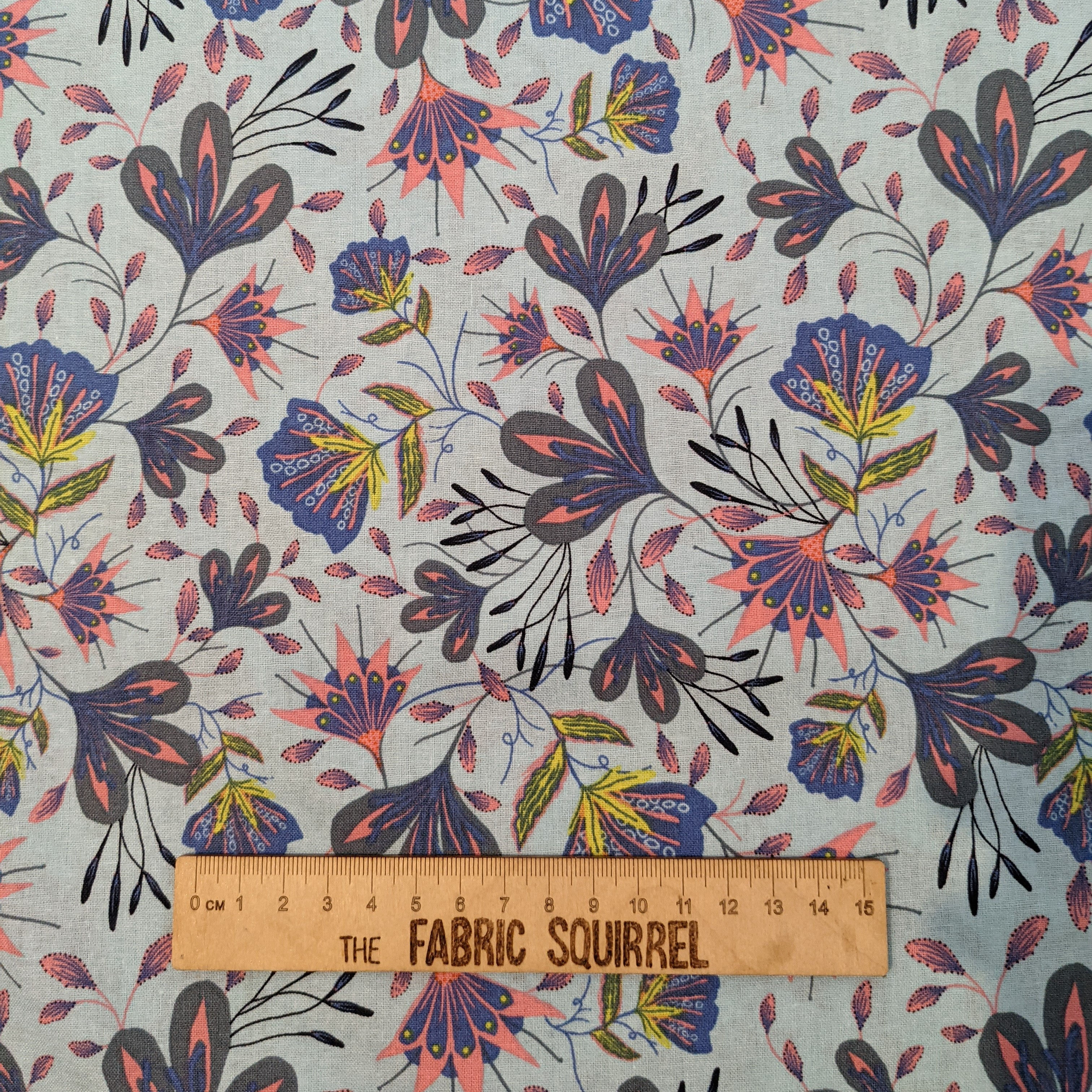 Floral fabric design with The Fabric Squirrel ruler, blue, pink, and purple flowers.