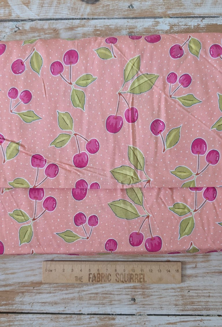Thumbnail: Pink fabric with cherries and leaves pattern with a ruler and dots.