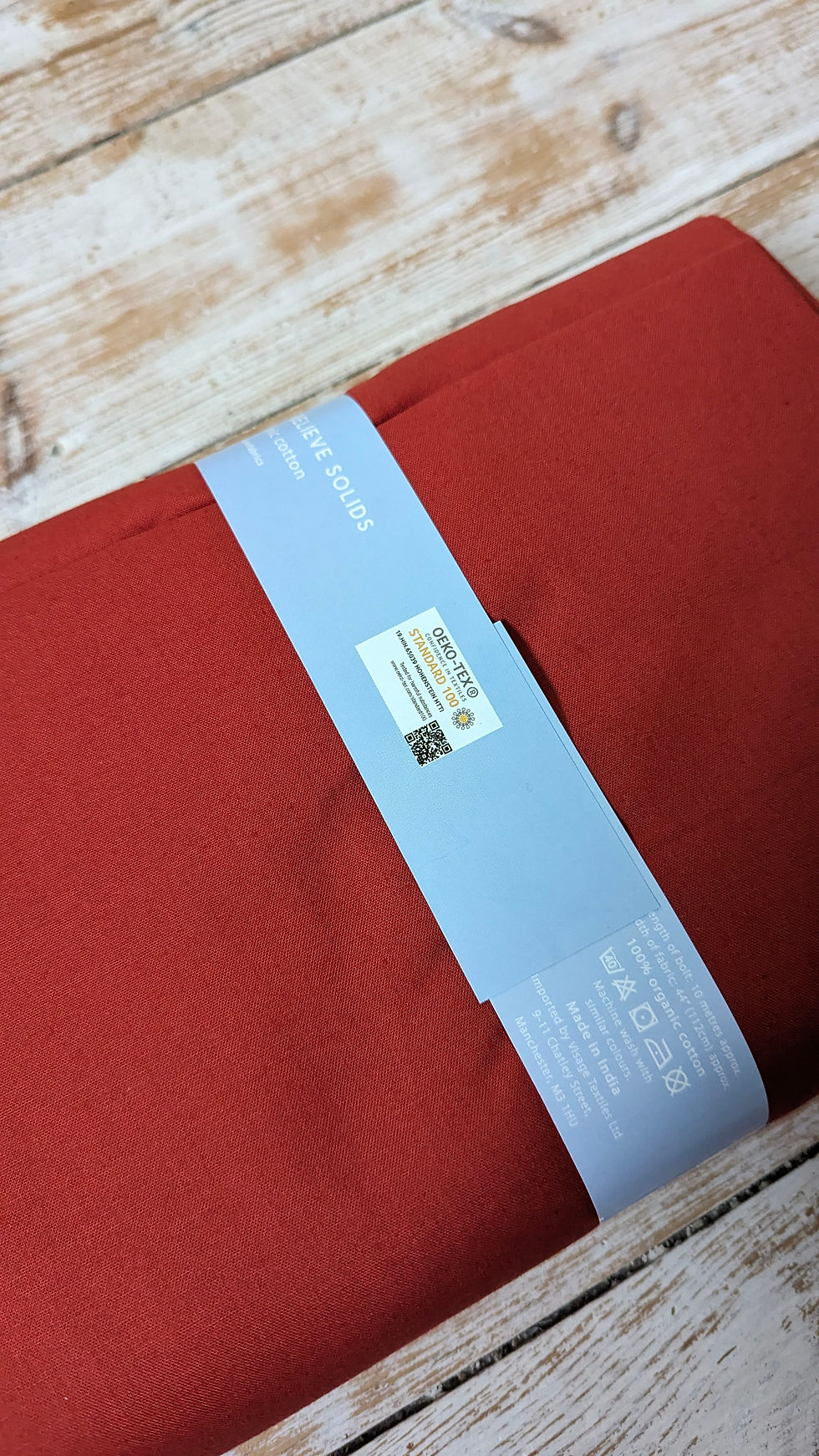 Thumbnail: Red fabric, with label text, rolled up, ready for crafting projects.