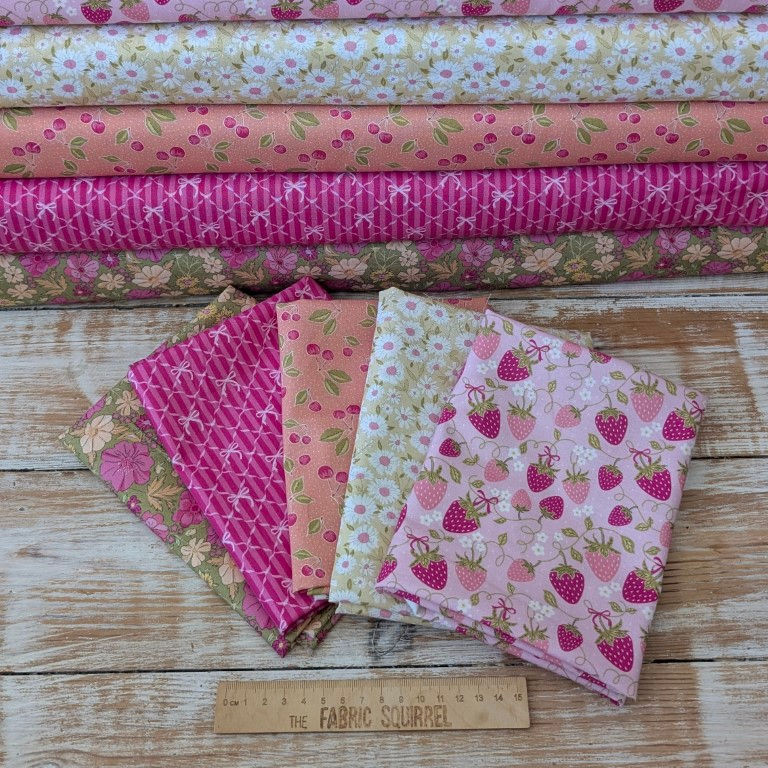 Various pink fabrics with floral and strawberry patterns with ruler and The Fabric Squirrel
