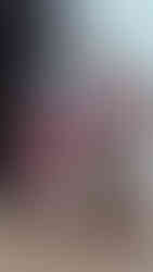 Christmas gift sack made from baby clothes filled with toys sat by a fireplace