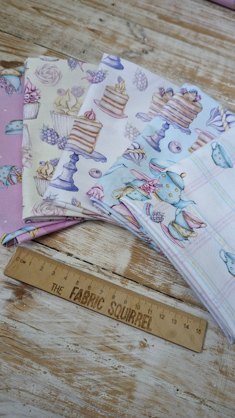Thumbnail: Various fabrics with cake designs and ruler reading The Fabric Squirrel, wooden background.