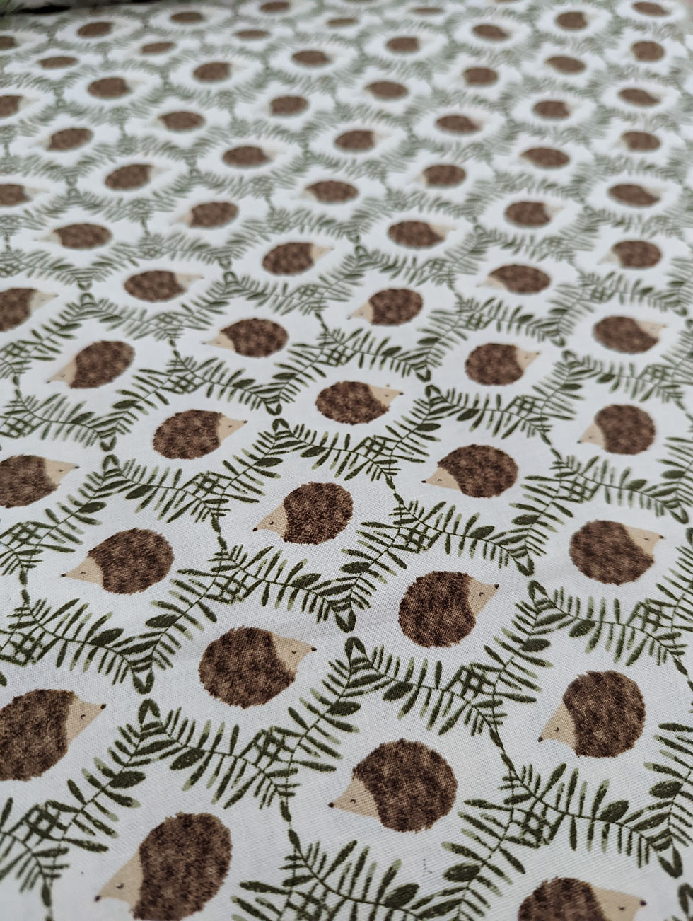Thumbnail: White fabric repeating hedgehog pattern with green leaves, The Fabric Squirrel.
