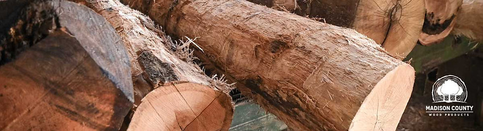 Logs stacked in a pile, with visible bark texture. Logo in the corner says "Madison County Wood Products." Earthy tones dominate the image.
