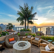 Rooftop lounge with fire pit, city skyline view at sunset