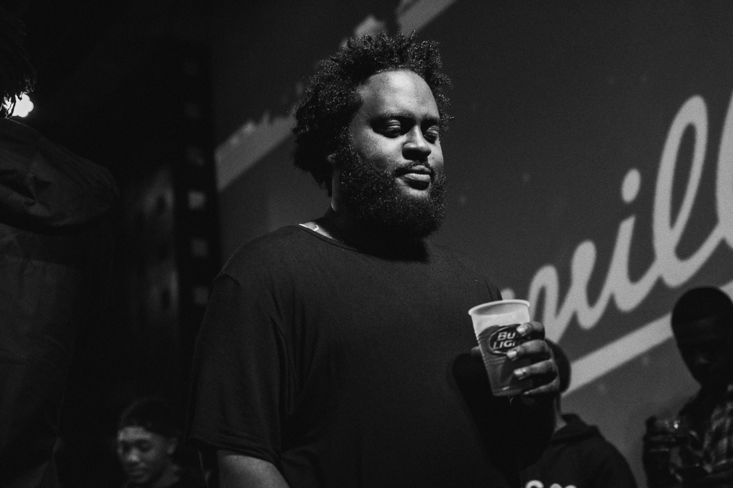 Dreamville artists Bas holds a Bud Light in his hand backstage