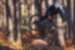 Enduro rider sending a jump on a Santa Cruz bike through a forest trail. Built for demanding enduro rides, featuring precision-engineered wheels and durable components for ultimate control and performance on rugged terrain.