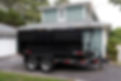 A contractors dumpster is on a trailer for easy hauling in their customers driveway..jpg