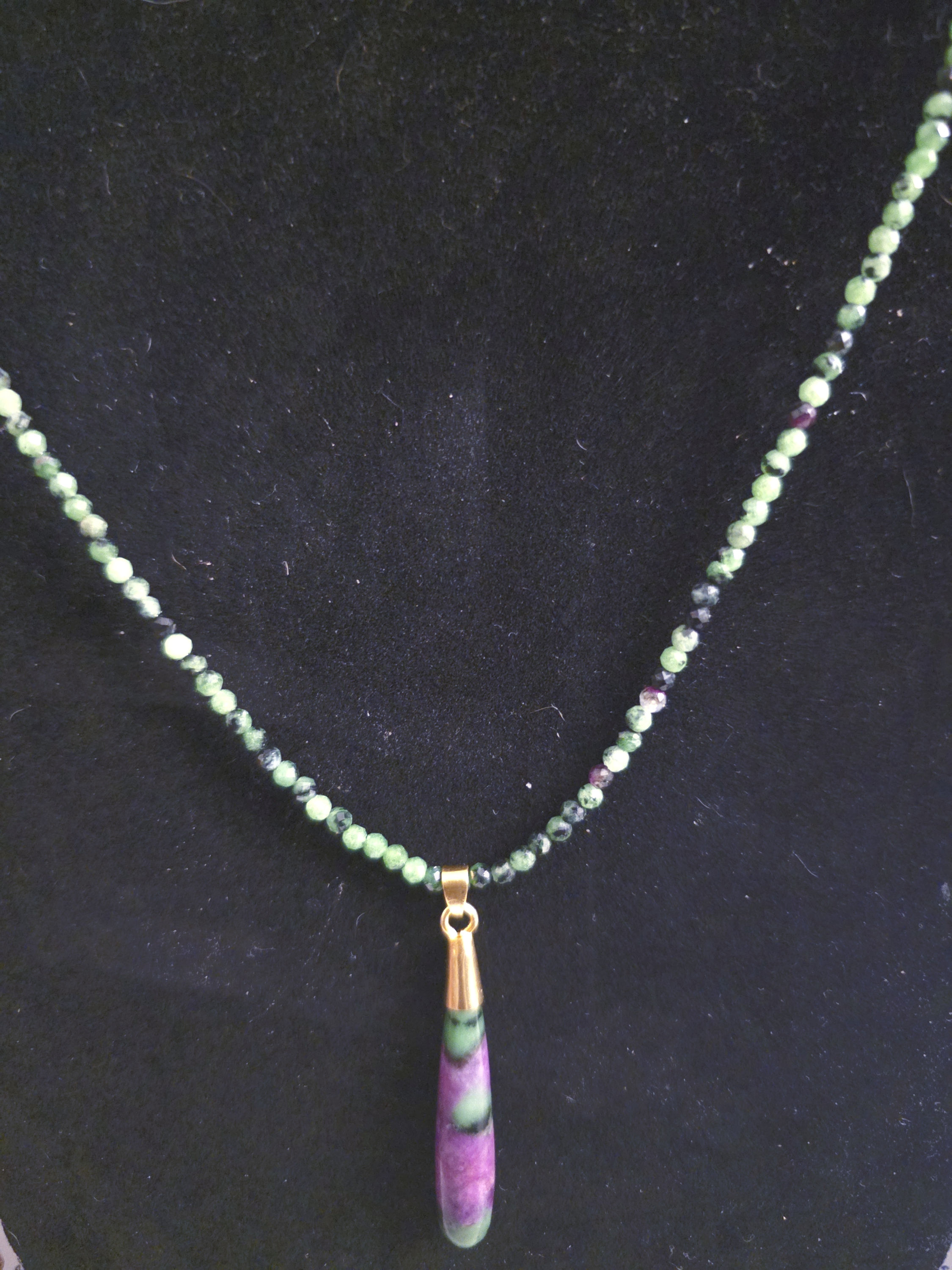 ruby in zoisite beads paired with a striking teardrop pendant wrapped in gold accents.