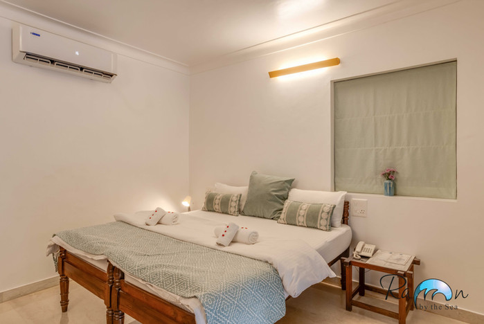 Neatly made twin beds with wall light above.